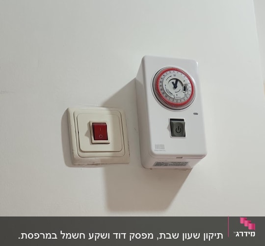 מתג חשמלי ושעון טיימר על קיר לבן